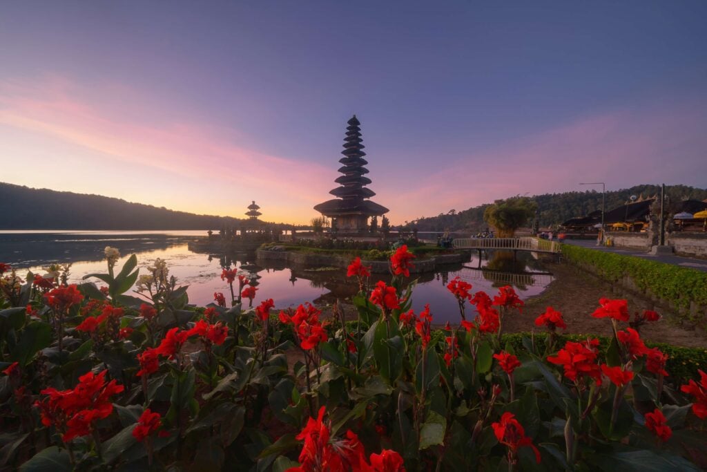Ulun Danu Bratan Temple, red flowers, and lake in Bali One of the most popular of tourist attraction Indonesia Hindu pargoda architecture of travel trip and holidays vacation in Indonesia