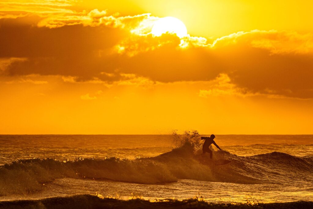 Scenic view of a surfer on the haves sea waves during sunset, Bloubergstrand, Cape Town