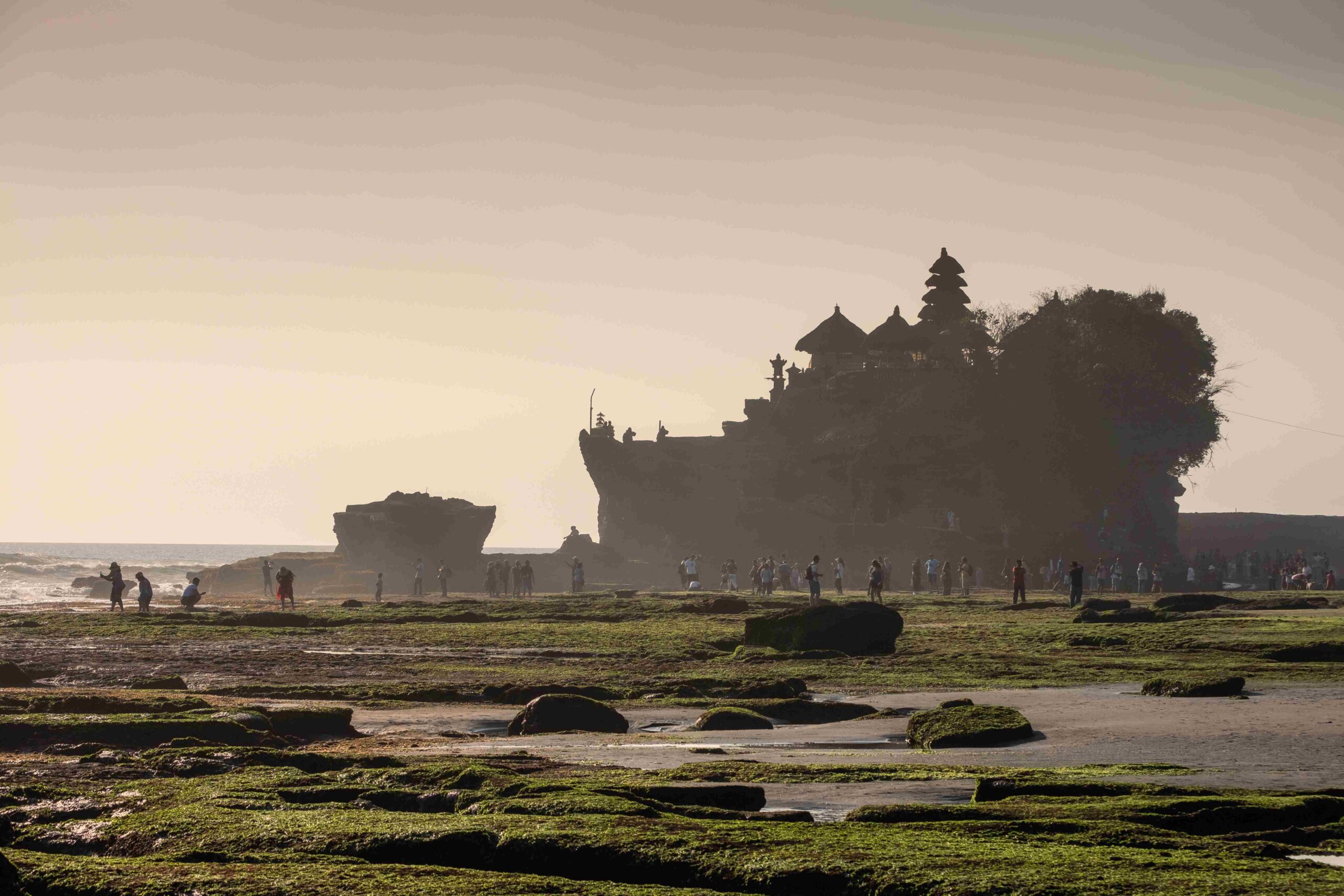 Ancient Tanah Lot temple with dreamy tourists on coastline