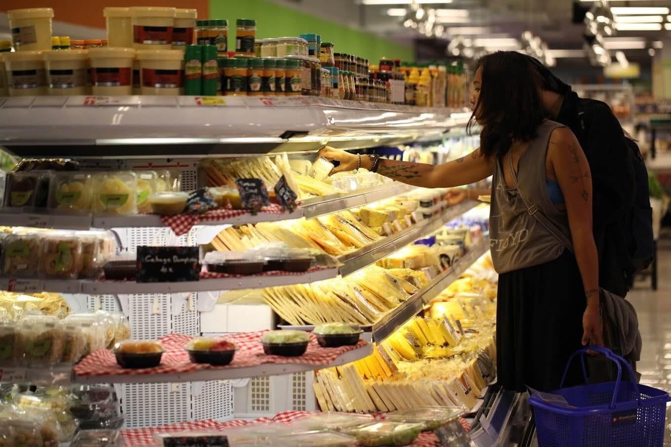A customer selecting from the variety of cheeses at Grand Lucky Supermarket in Seminyak