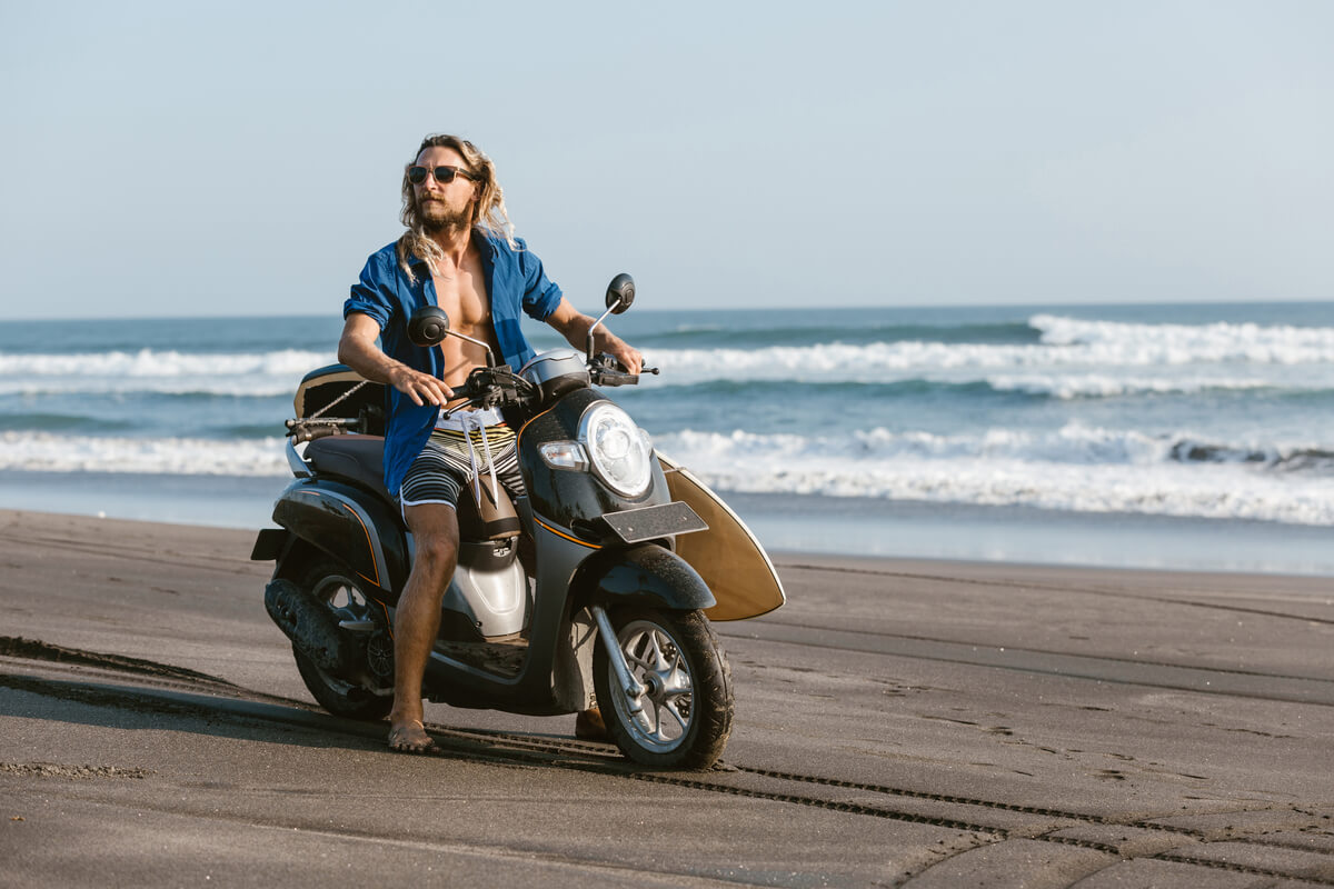 A traveler on a rented scooter, taking a ride on Bali with surfboard