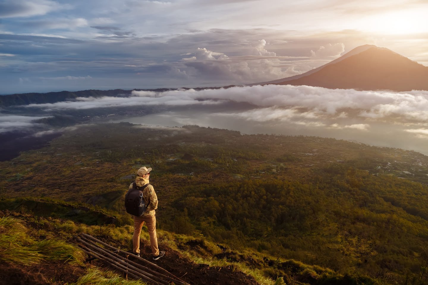 Man tourist looks at the sunrise on the volcano batur