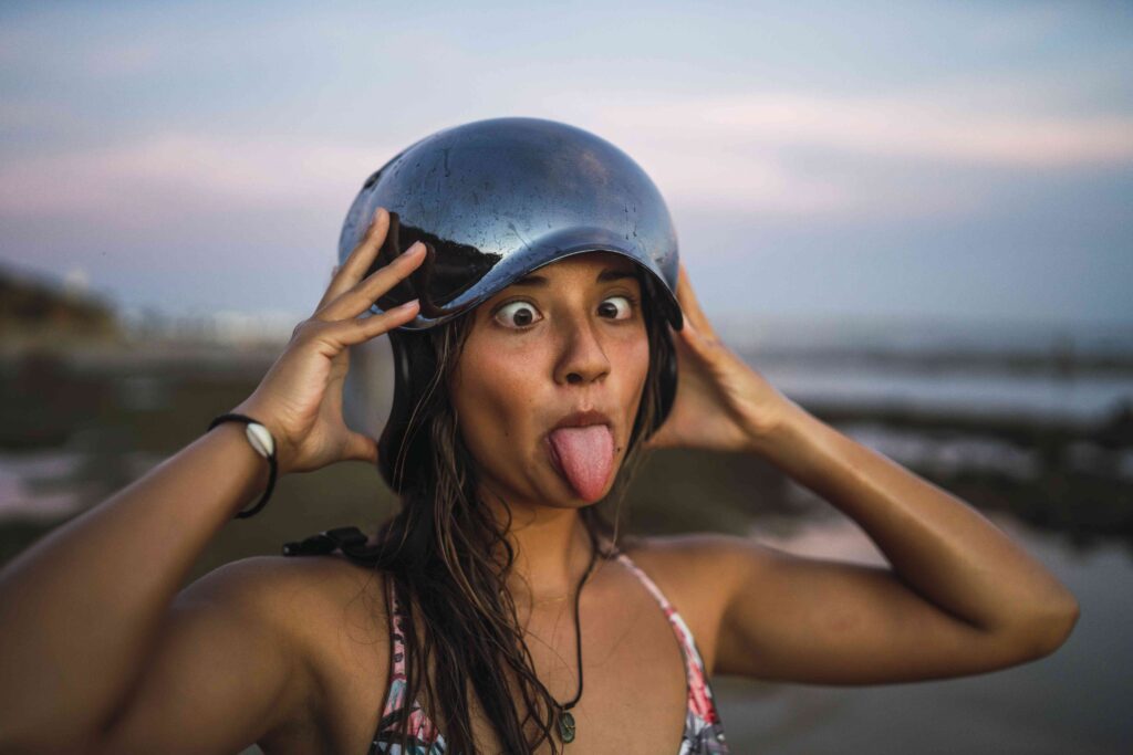 Shallow focus of a young female with a helmet making a funny face at the beach of Chiclana, Spain