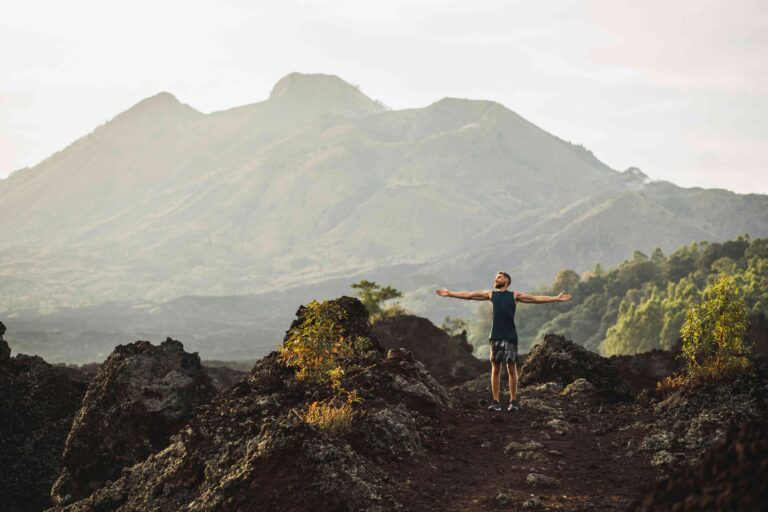 Young happy man hiking and enjoying amazing volcanic mountain Batur