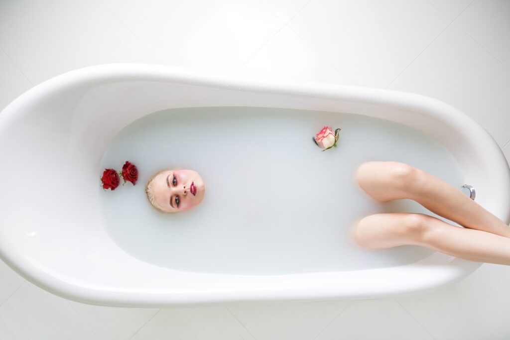 Beautiful young woman taking bath with milk