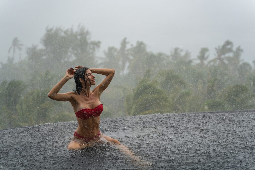 Cute tanned Caucasian girl bathing in the rain