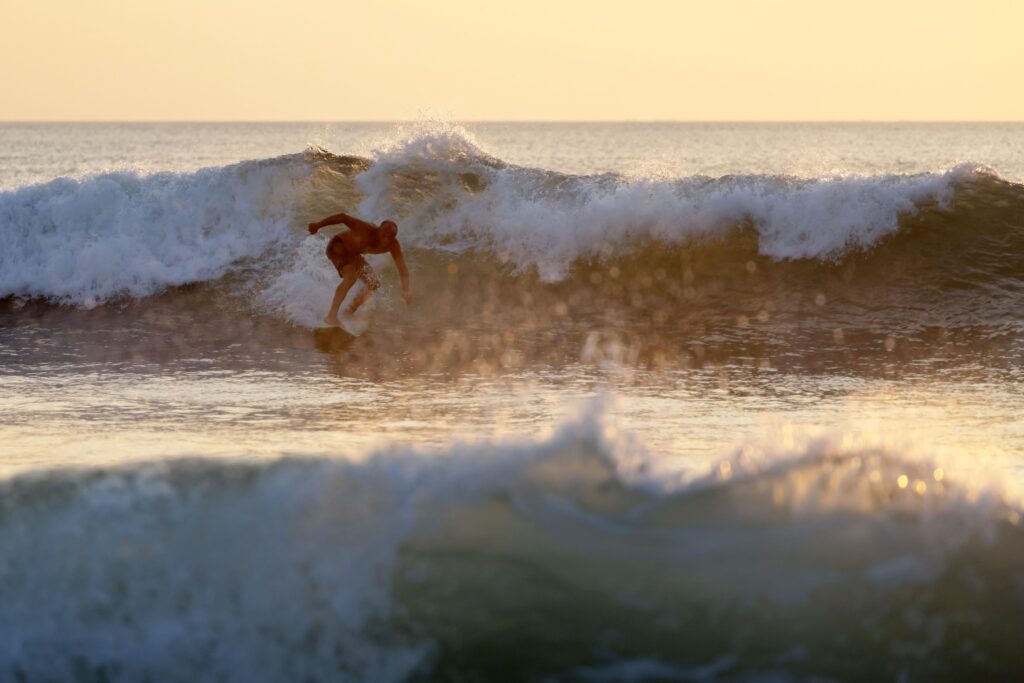 man surfing in bali indonesia kuta beach at sunset