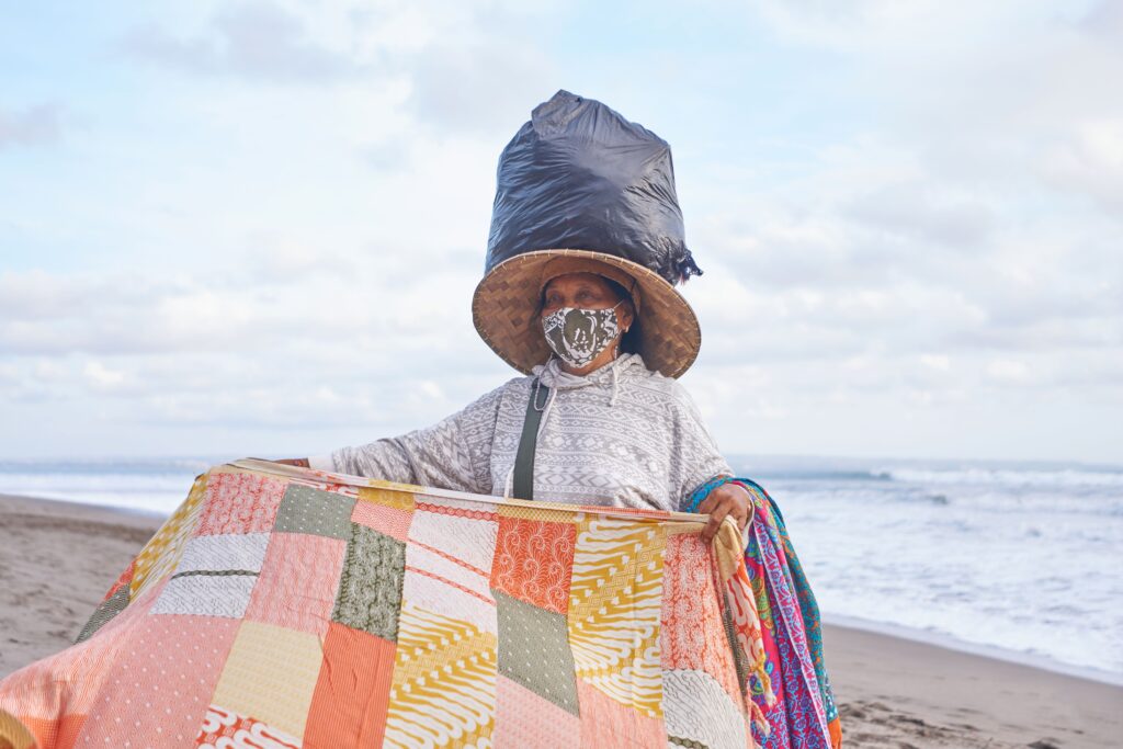 Old woman trading colorful veils staying on beach in bali