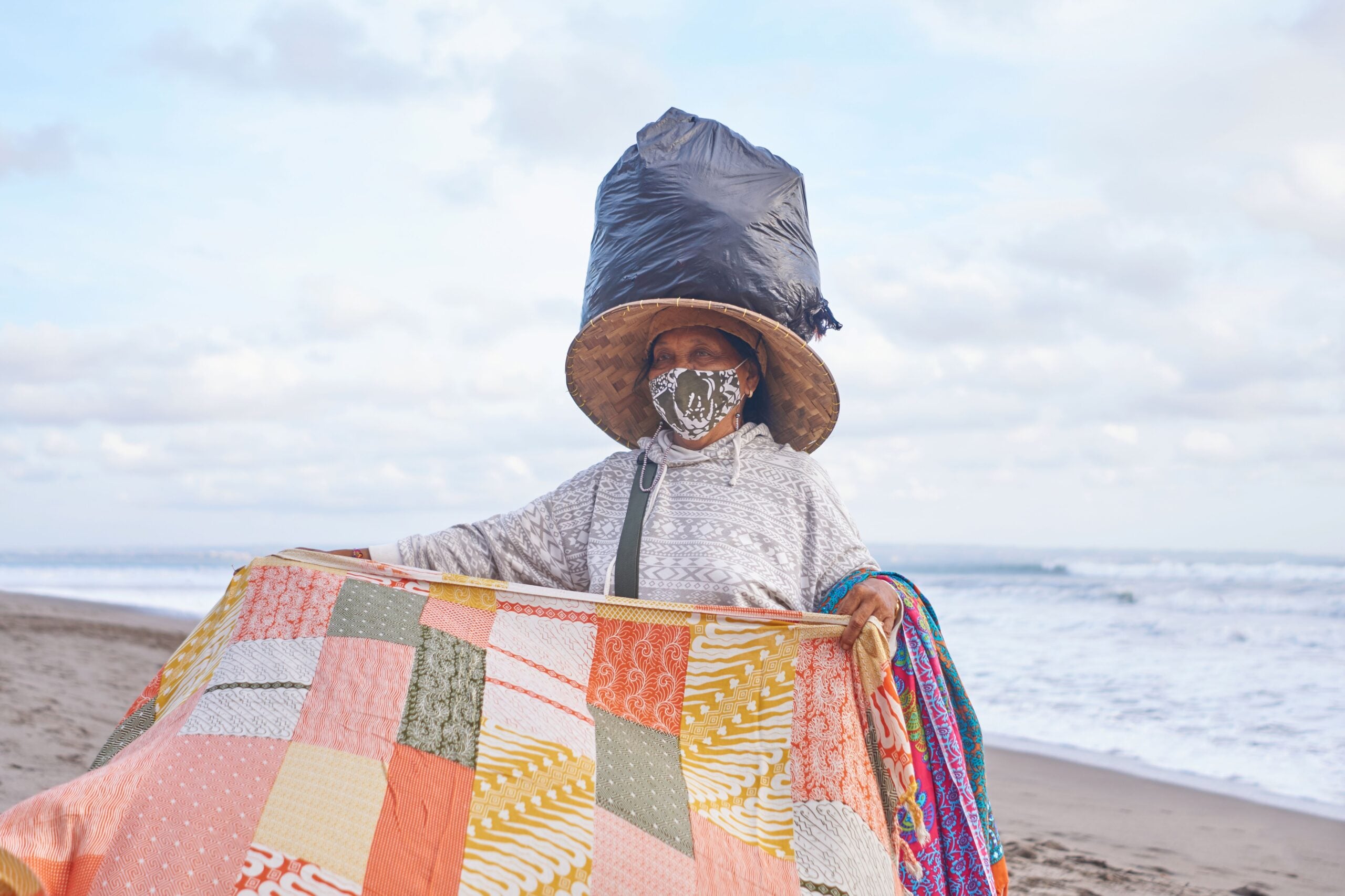 Old woman trading colorful veils staying on beach in bali