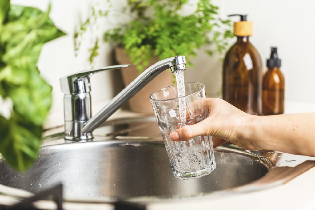 Female hand filing a glass with clean tap water