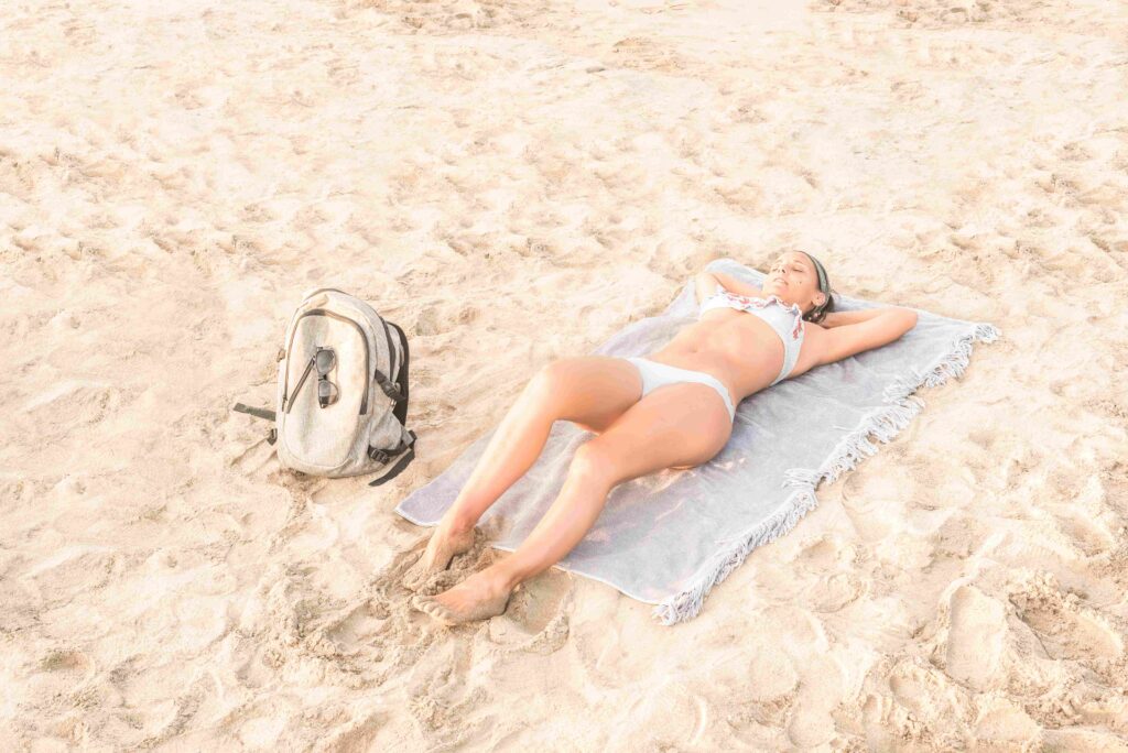 Young woman in swimwear resting on sandy shore