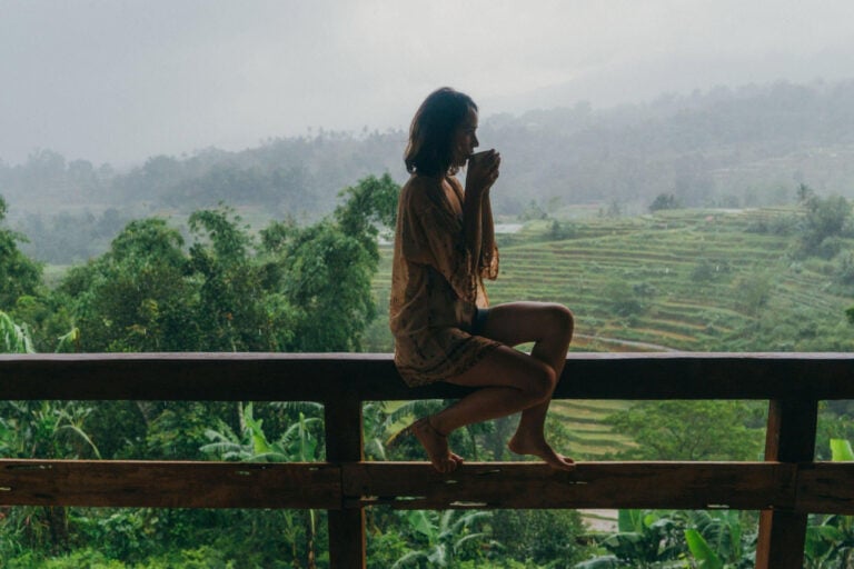 Young girl having tea in a balcony with rice fields view in Bali