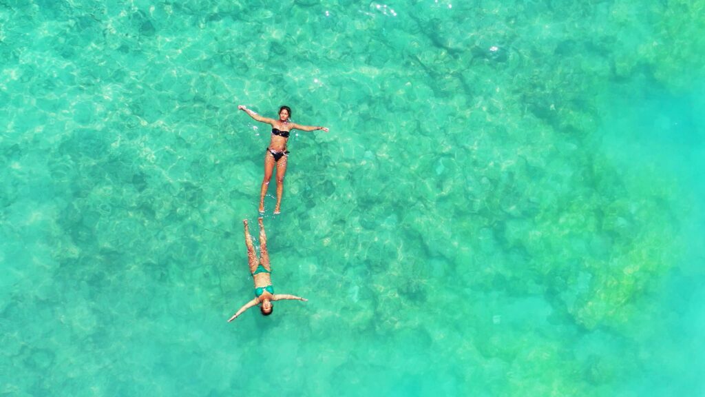 Aerial Shot girls swim in the turquoise, clear water of Gili Meno Island, Lombok, Indonesia.