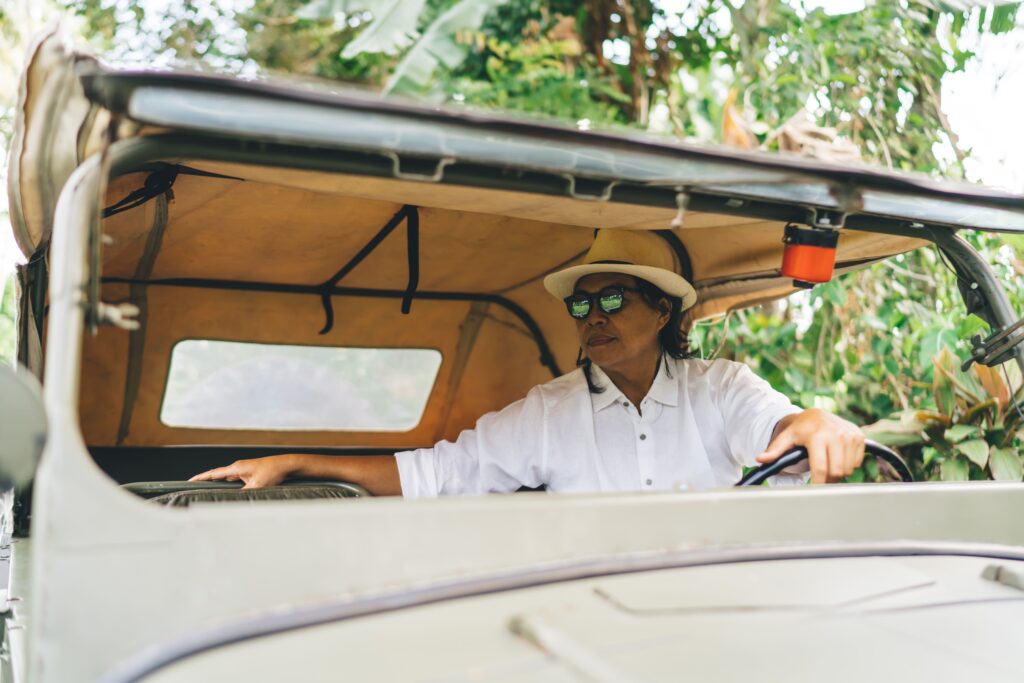Ethnic man with hat and sunglasses sitting in offroader