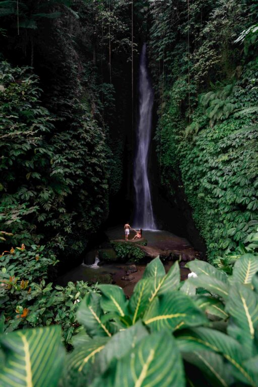 Young couple tourism enjoying the Leke Leke waterfall at Bali in Indonesia