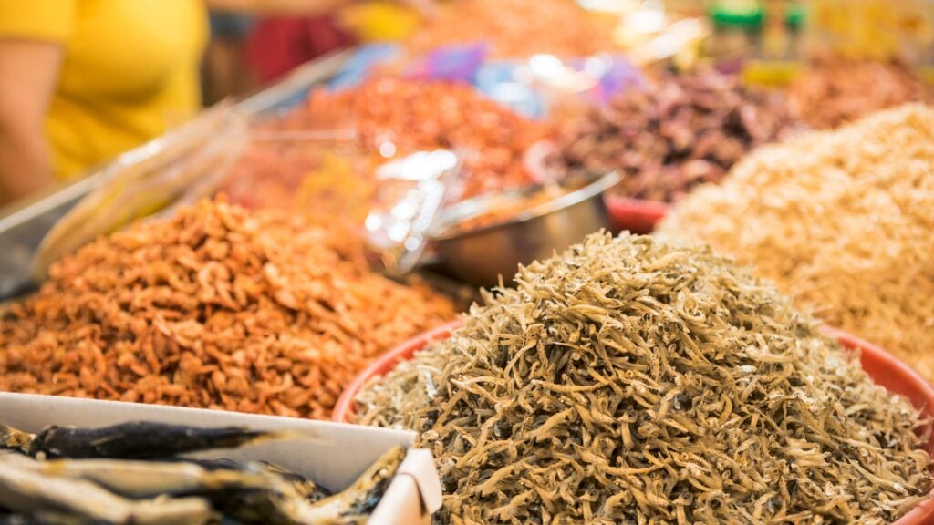 A stall vendor selling dry shrimp fish and various ingredients in popular market