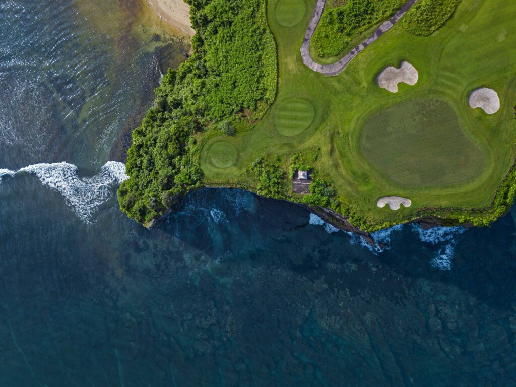 Aerial view of golf course with green at coast