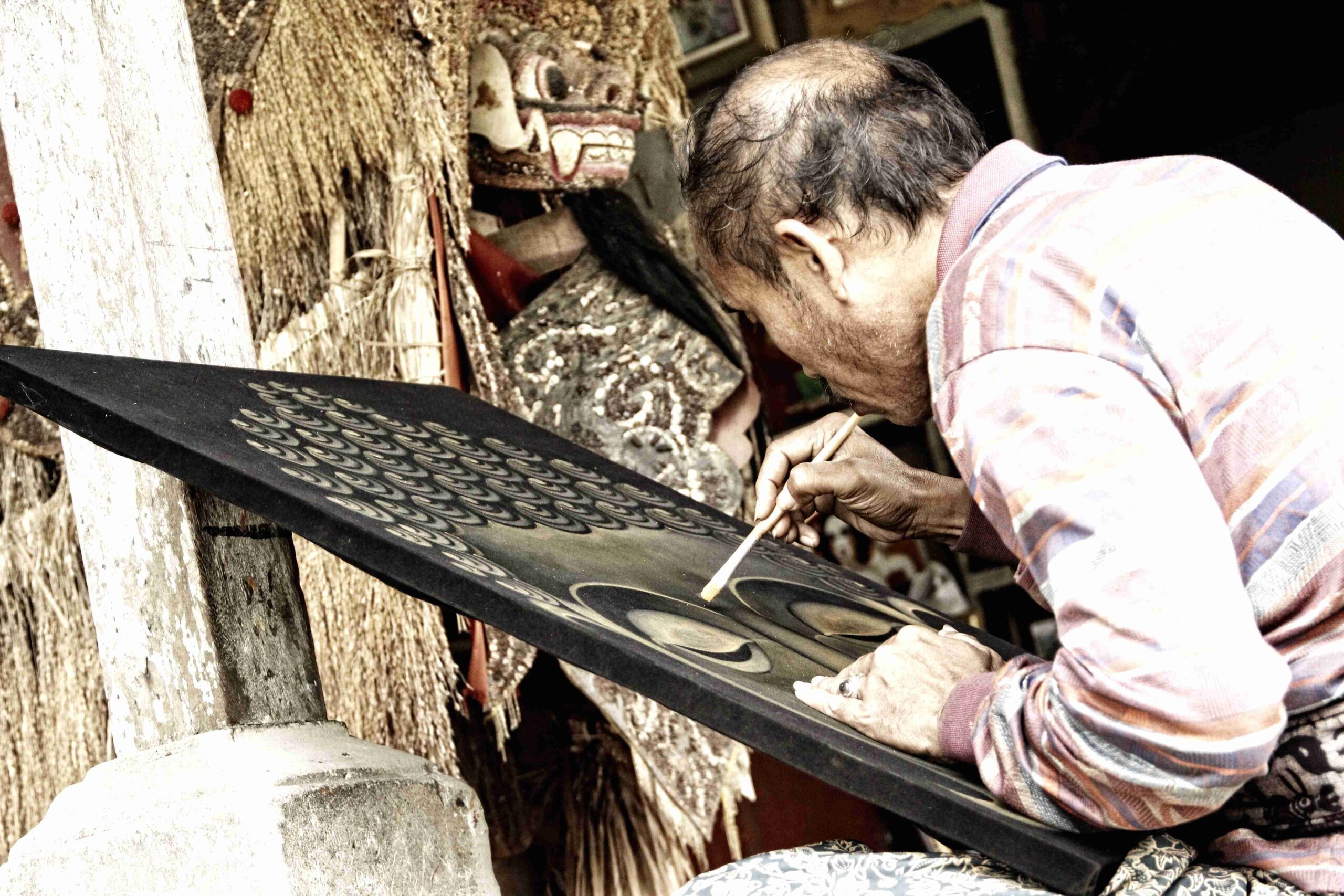 An elderly painter at The Royal Family Temple in Bali painting a Buddha Indonesia