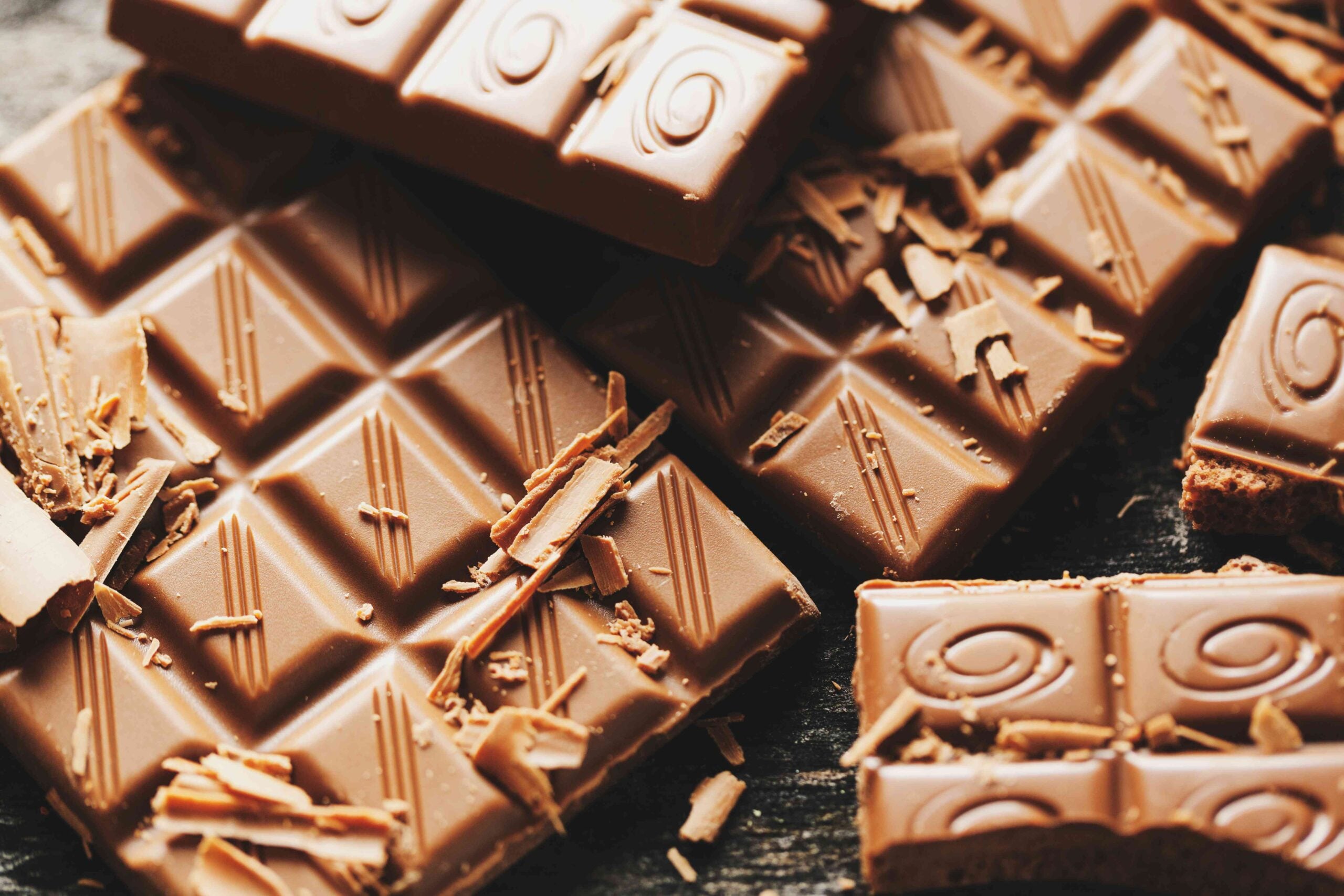 Broken chocolate bars on dark background