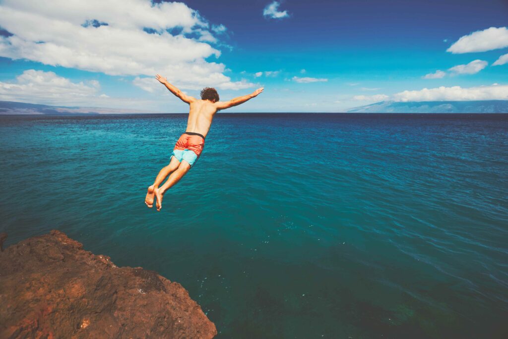 Friends cliff jumping into the ocean