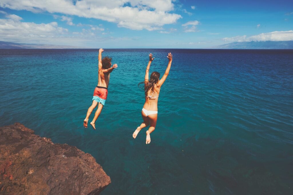 Friends cliff jumping into the ocean