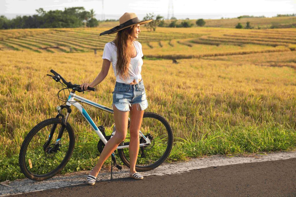 Happy woman with a bicycle on side of the road