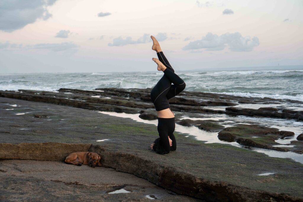 Headstand on the beach Young attractive woman practicing yoga in Bali