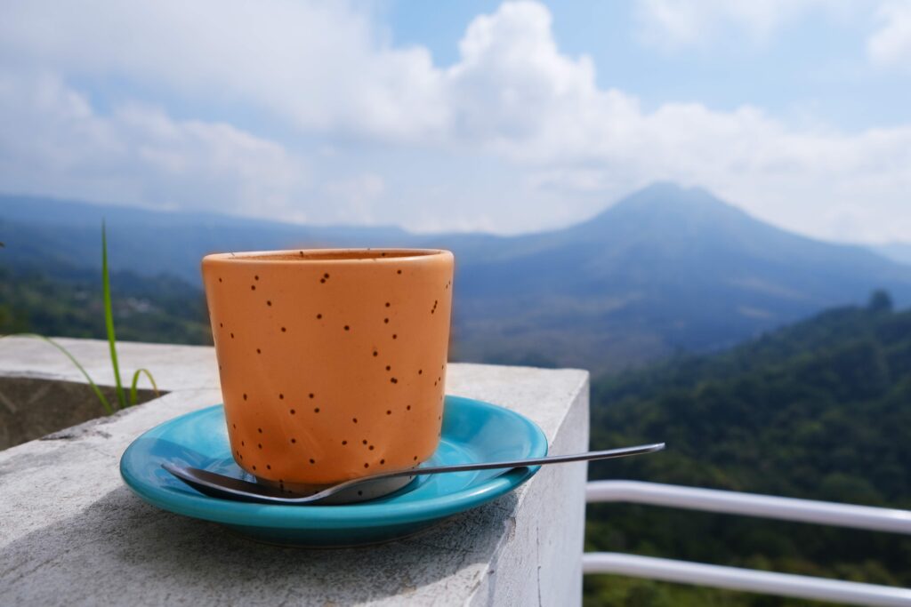 peach fuzz color of mug of hot cappuccino with volcano view in Bali