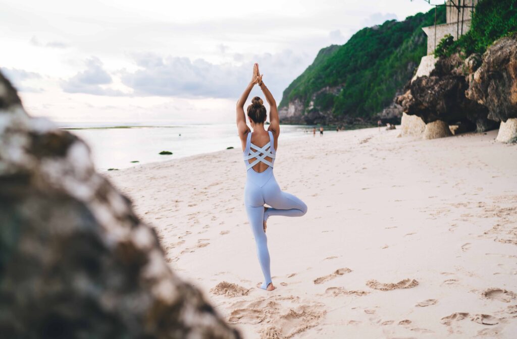 Slim faceless woman practicing yoga on beach