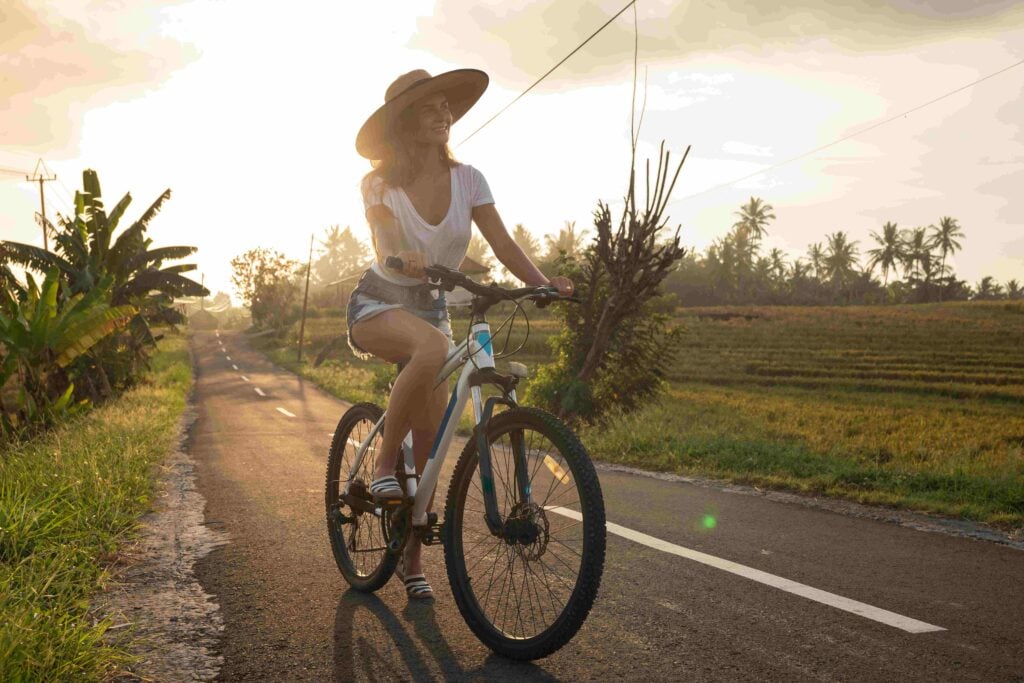 Woman is riding bicycle by narrow country road