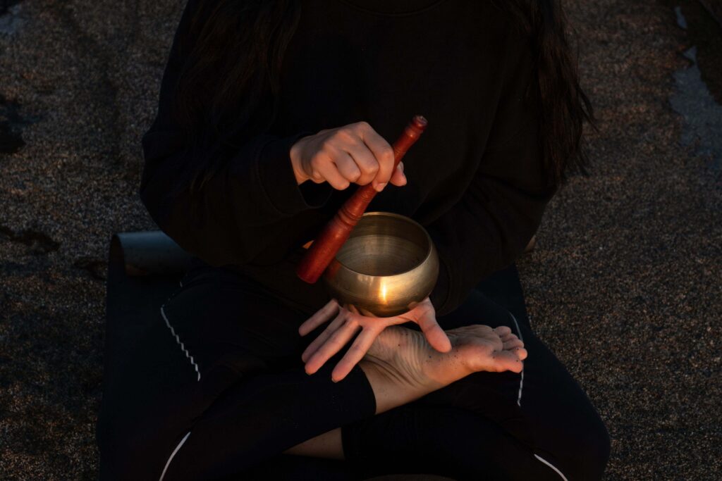 Woman playing Tibetan singing bowl during a meditation and relaxation session in Bali beach