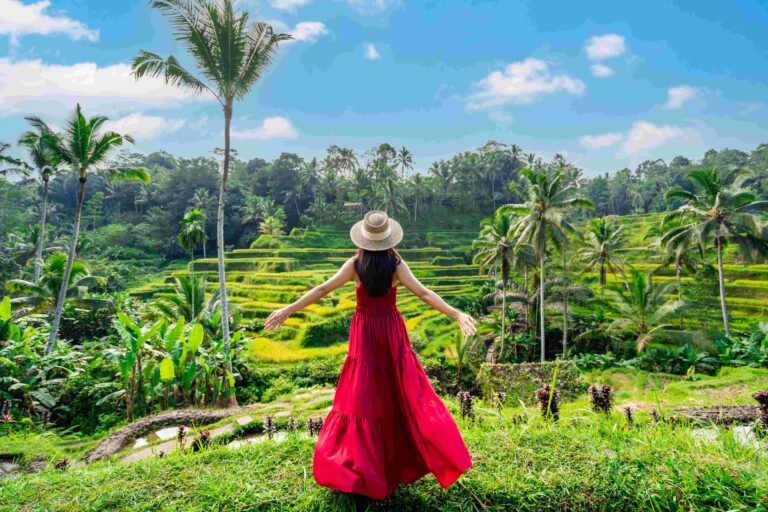 Young female tourist in red dress looking at the beautiful tegalalang rice terrace in Bali, Indonesia