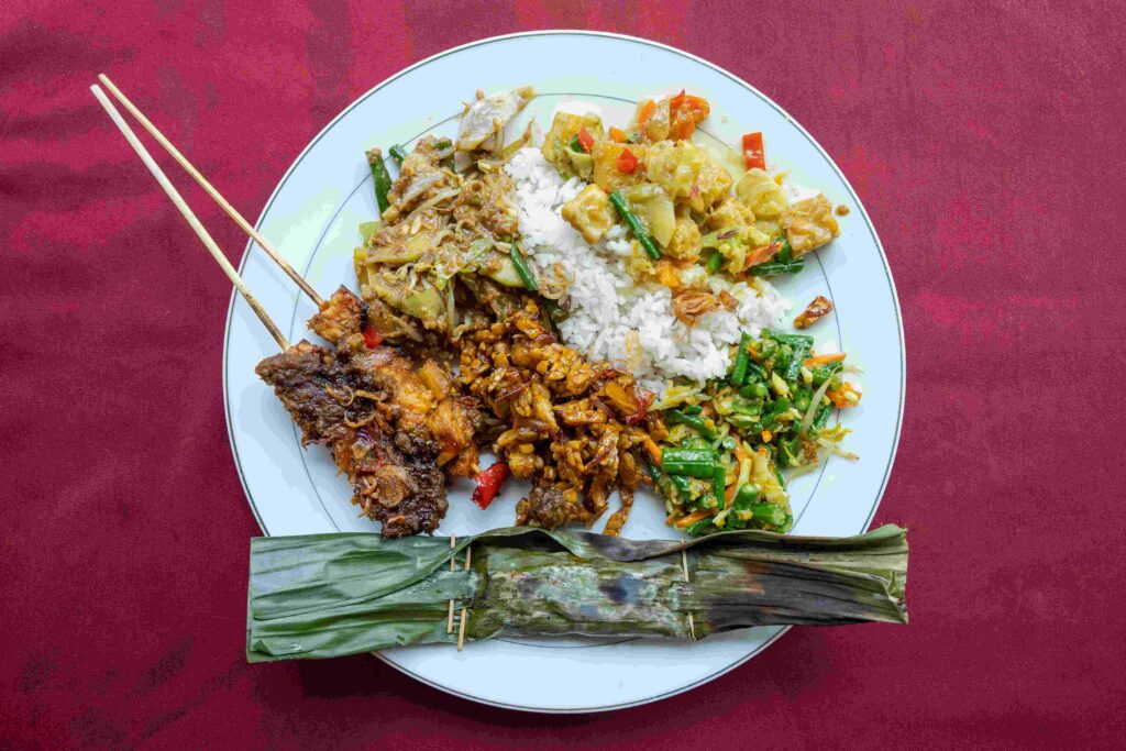 A plate of Indonesian vegtarian Nasi campur (Indonesian for mixed rice) with sate