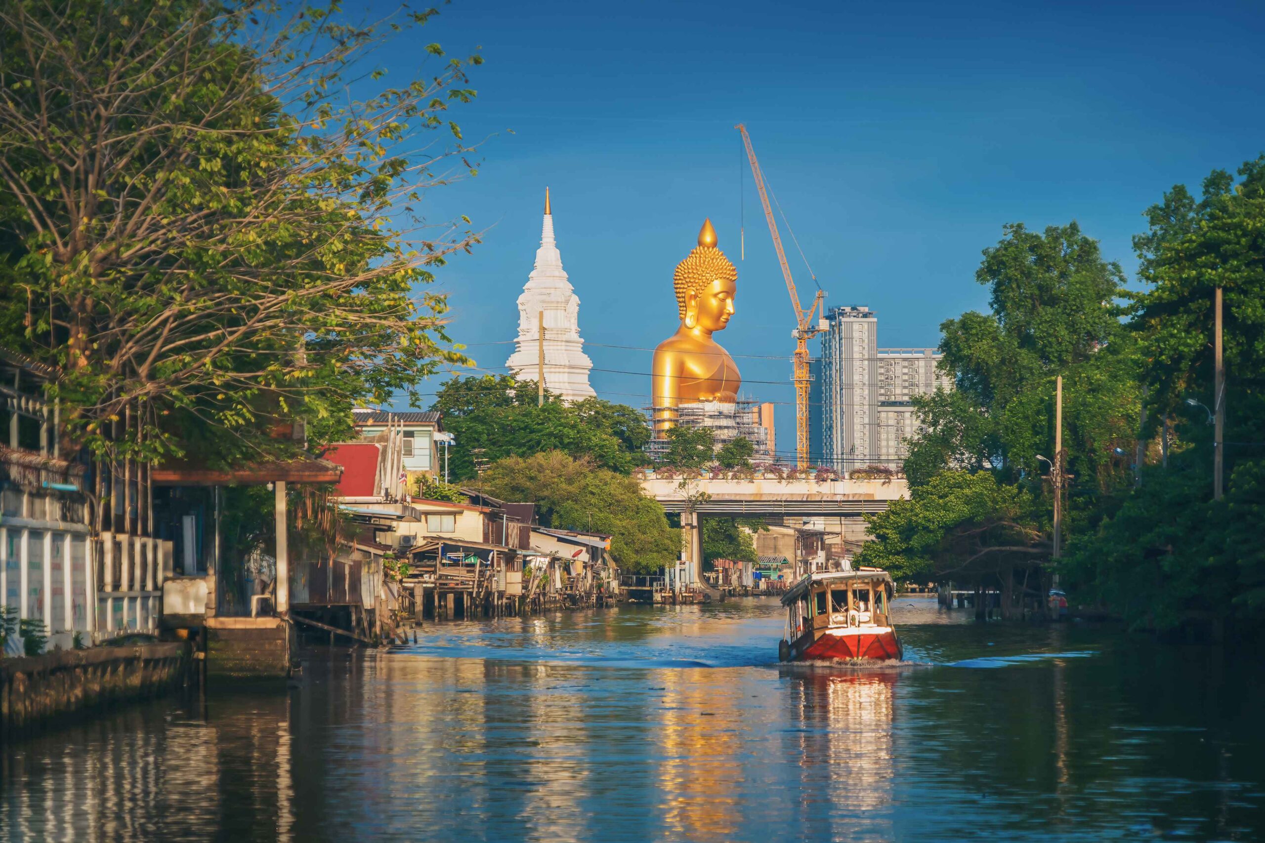 The Giant Golden Buddha in Wat Paknam Phasi Charoen Temple in Phasi Charoen district with boat on Chao Phraya River, Bangkok urban city, Thailand