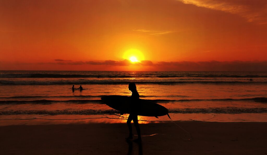 women with surfboard during sunset