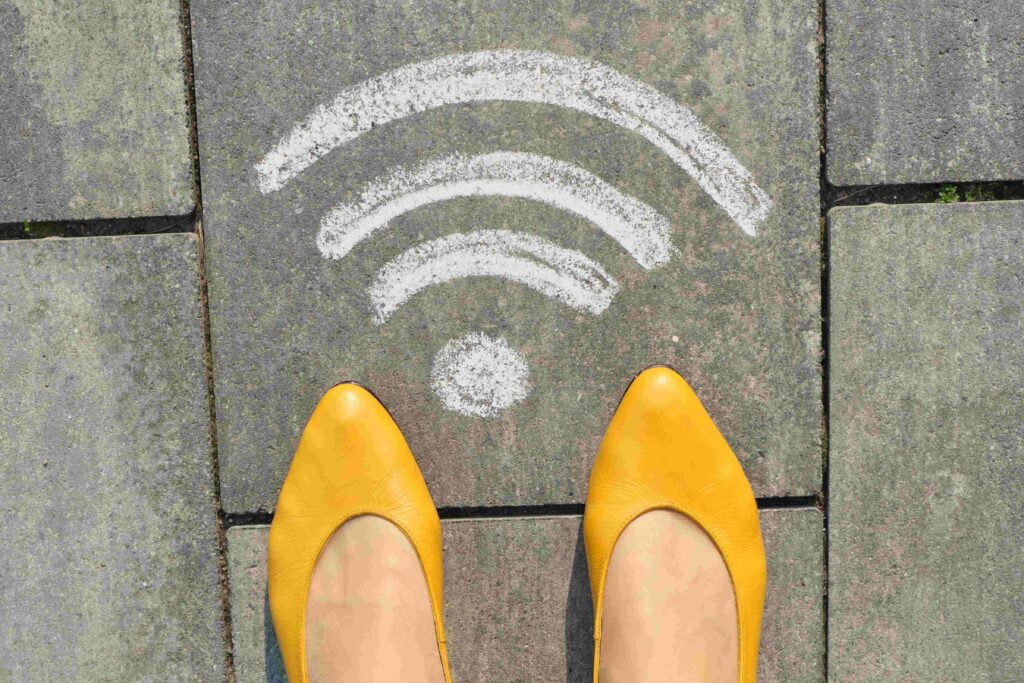 Wi fi symbol on gray sidewalk with woman legs, top view