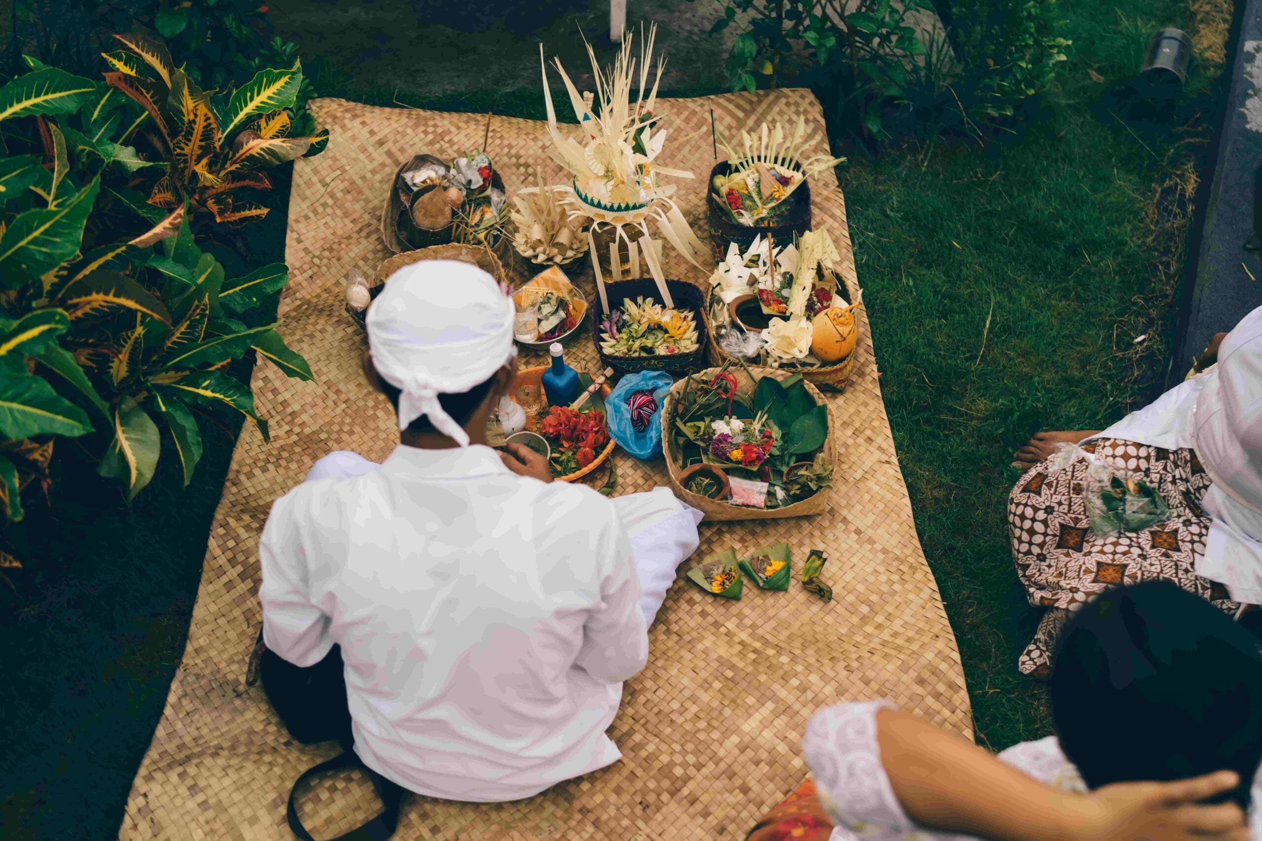 Balinese priest doing ritual on sackcloth in countryside