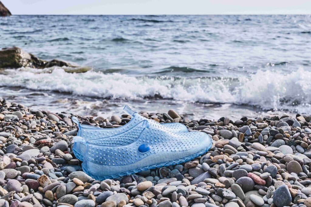 Rubber blue women's slippers for swimming on a pebble beach