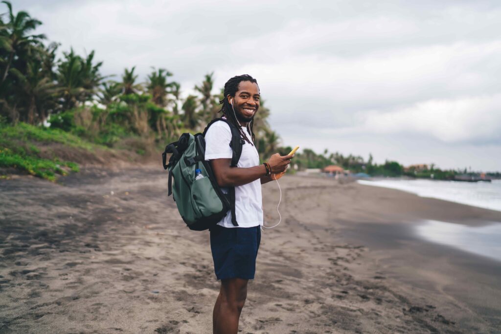 Smiling black guy standing on beach