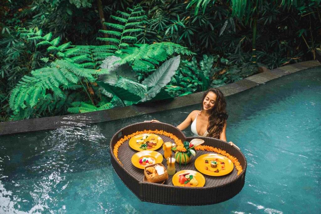Woman relaxing and having floating breakfast in jungle pool on l