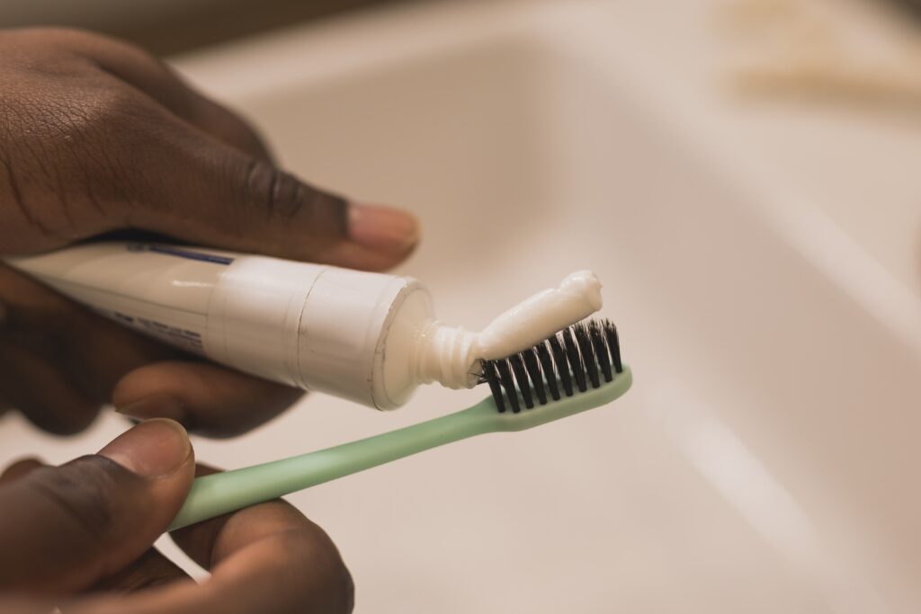 African american male hand holding toothbrush with toothpaste applied on it in bathroom Close up of man hand ready for brushing teeth Guy hand holding toothbrush with white tooth paste