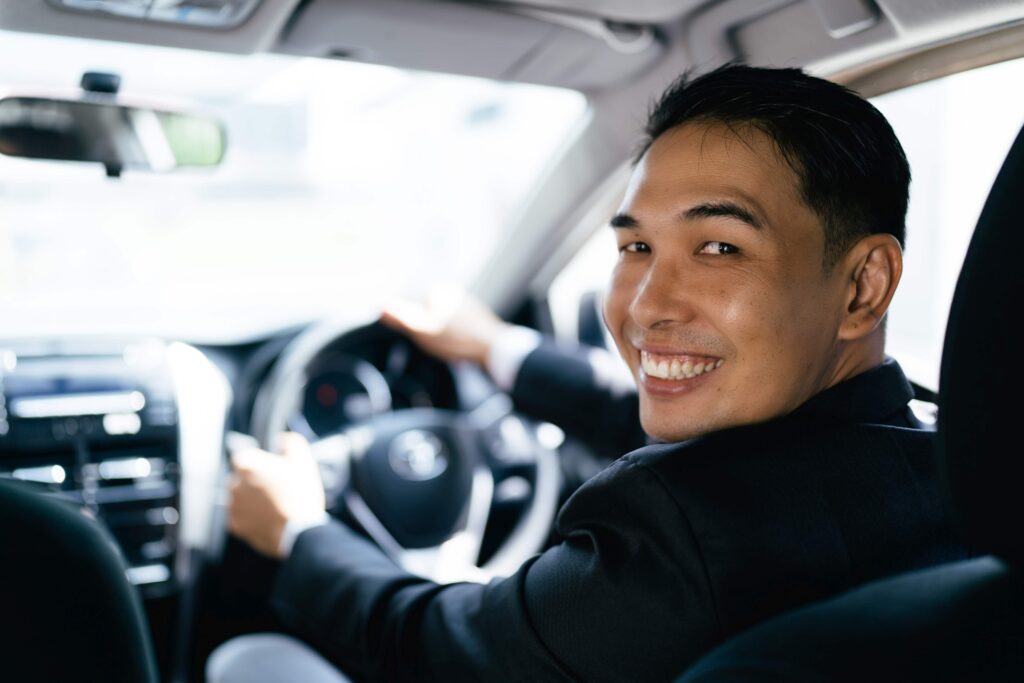 Asian businessman driving car and smile, car insurance concept