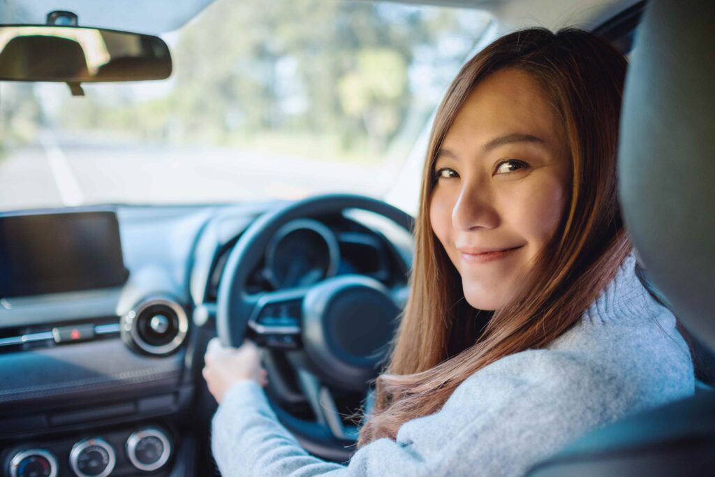 Closeup image of a woman holding steering wheel while driving a