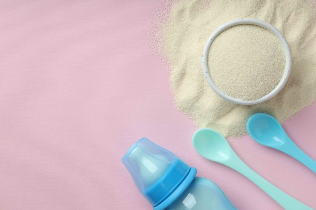 Concept of baby food with рowdered milk on pink background