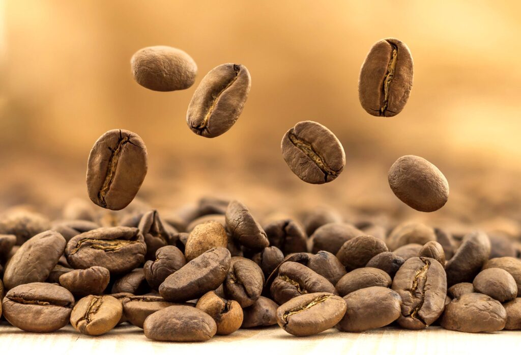 Flying fresh coffee beans on yellow blurred background with copy space Coffee beans falling down