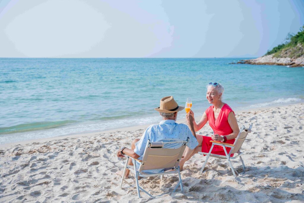 Senior couple relaxing and drink orange juice at tropical beach , Healthy seniors lifestyle concept