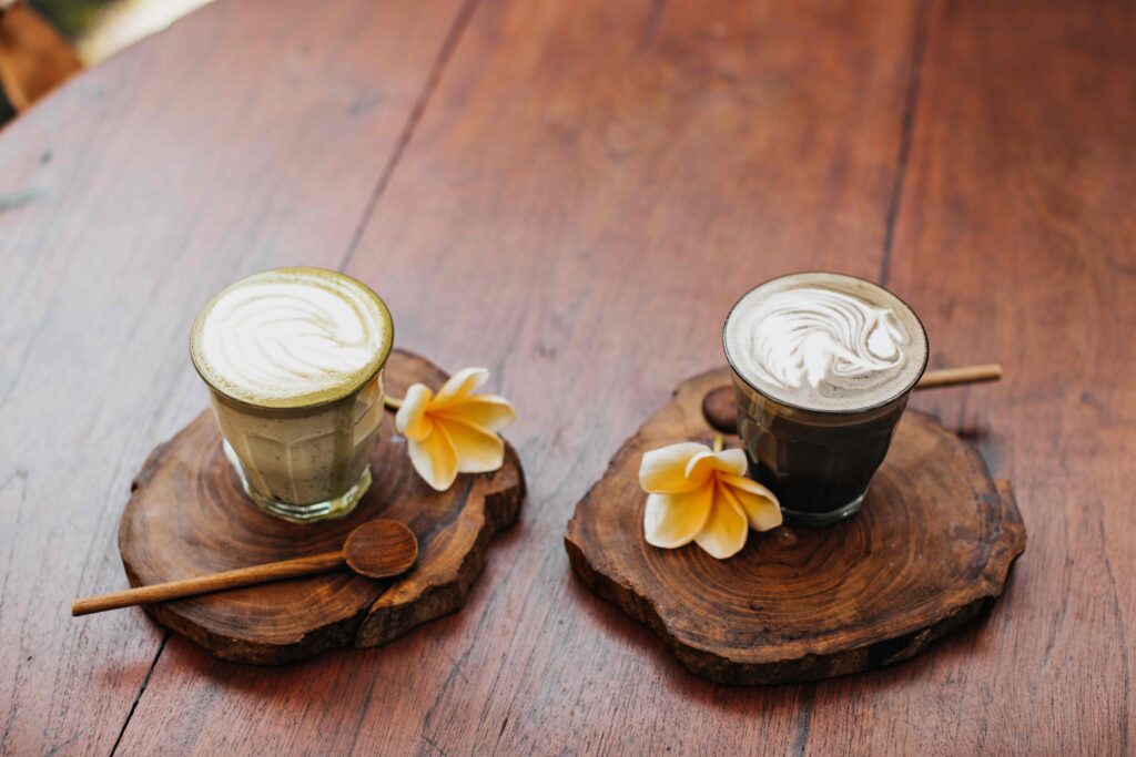 Snapshot of cup of matcha latte green tea, coffee with coconut milk, yellow tropical flower, wooden