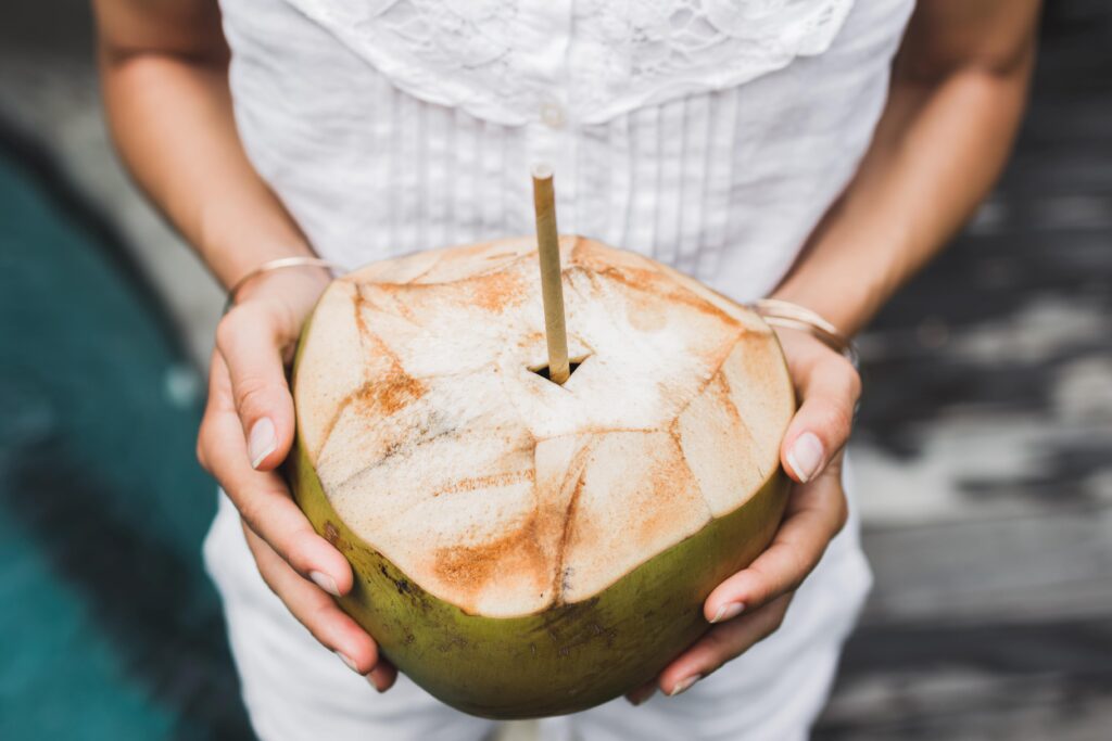 Woman hands holding cold and fresh young coconut Bali tropical
