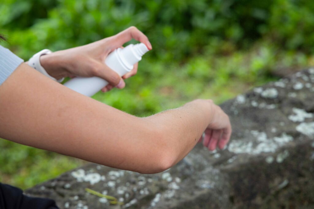 Woman spraying insect repellent at her hand