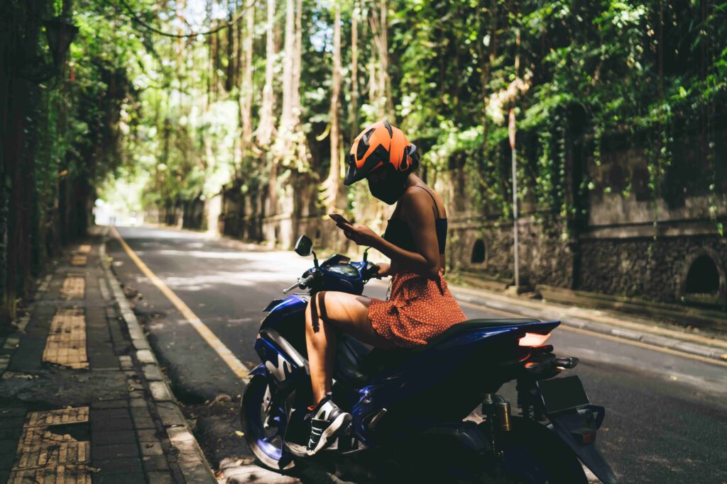 Anonymous woman browsing smartphone on motorbike